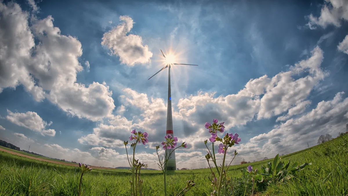 Man sieht eine grosse Windkraftanlage in der Natur.